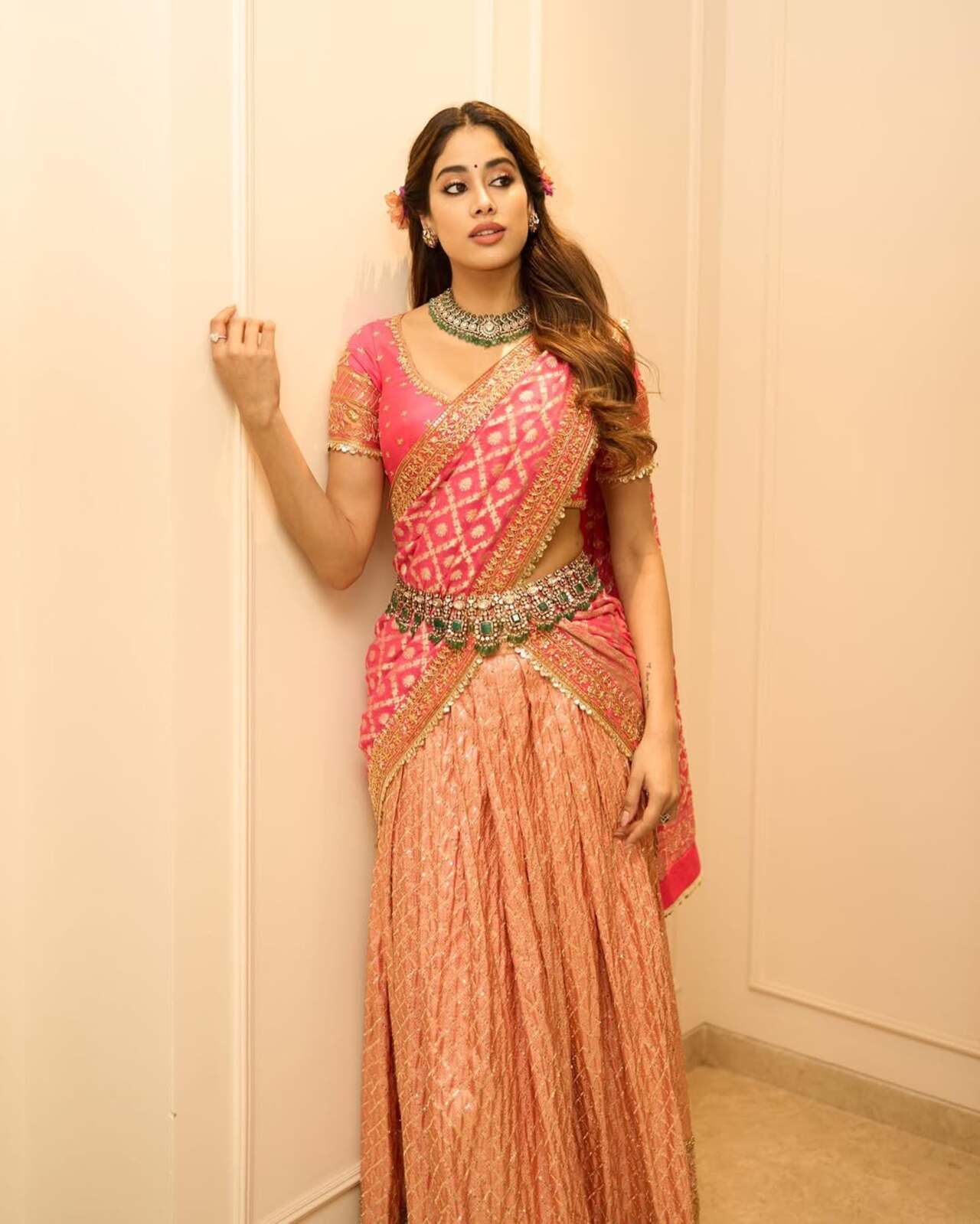In a bright pink and peach half saree, Janhvi channels regal charm with a statement waist belt and traditional jewels. A bold yet graceful look for festive evenings